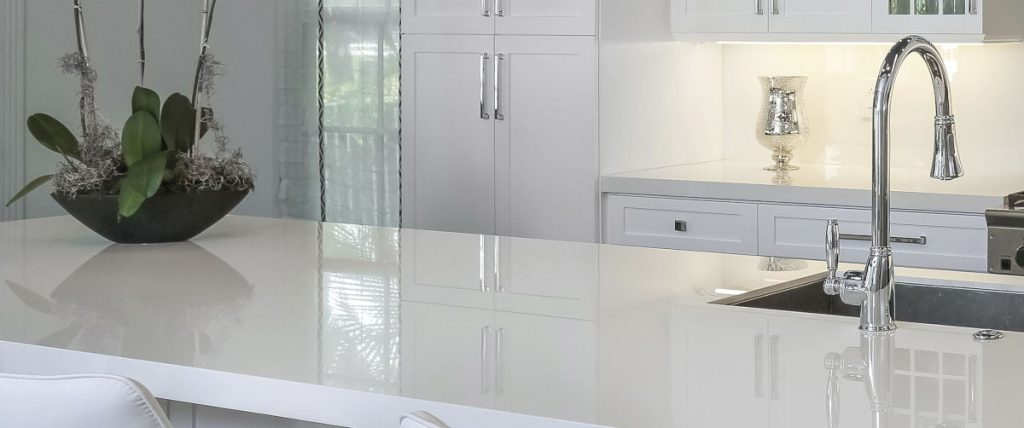 Parlak beyaz Ascale Infinity White porselen mutfak ada tezgahı ve beyaz dolaplarla modern mutfak tasarımı.