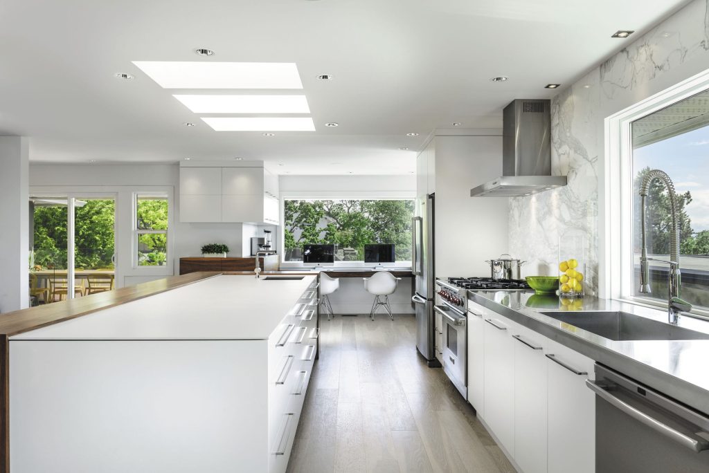 Modern mutfakta kullanılan Ascale Infinity White porselen ada tezgah, ahşap bar ve mermer desenli duvar paneli uygulaması.