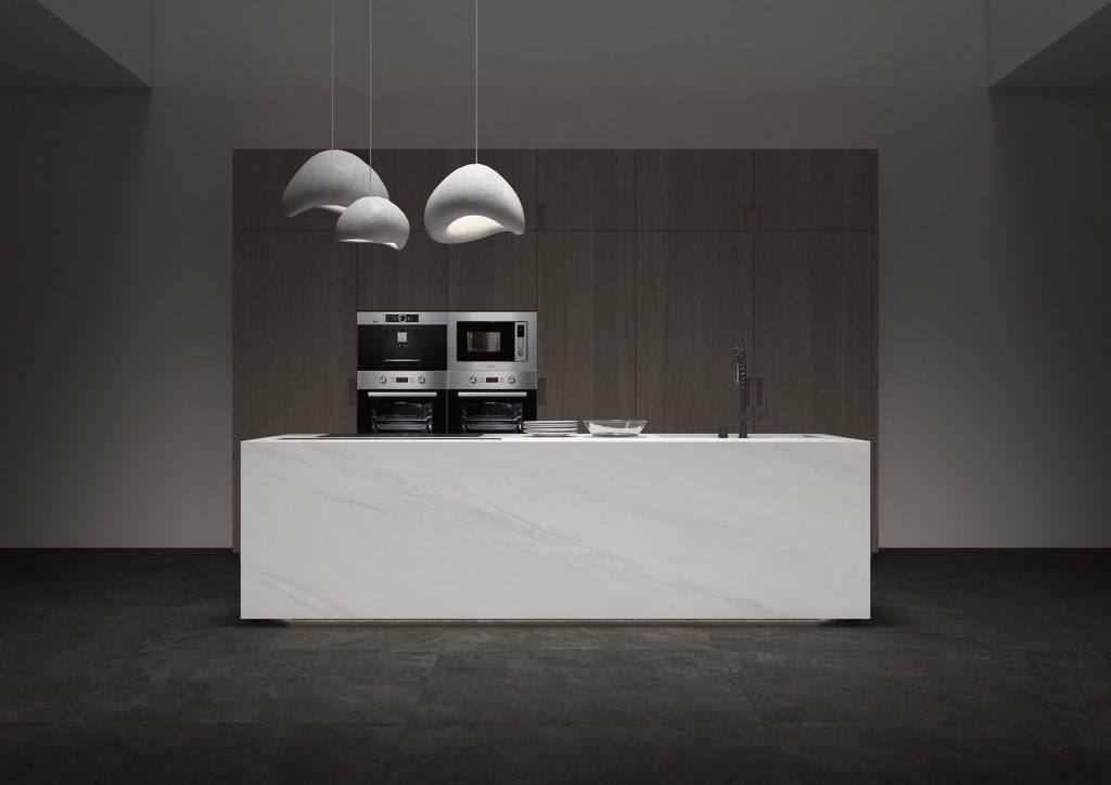 Gri damarlı Ascale Lasa White porselen mutfak adası, koyu ahşap dolaplar ve modern aydınlatmalarla minimalist bir tasarım.