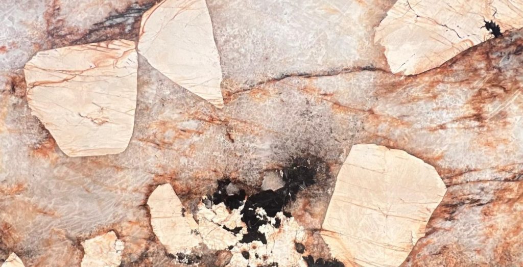 Bej ve kahverengi parçalı, kristal dokulu Marazzi Patagonia porselen tezgah yüzeyi. Siyah ve gri damarlar içerir.