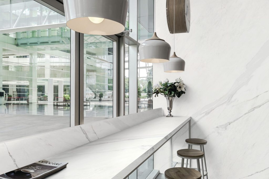 Gri damarlı beyaz Lapidura Calacatta White porselen yüzeyin bar tezgahı ve duvar kaplaması olarak modern bir mekanda kullanımı.