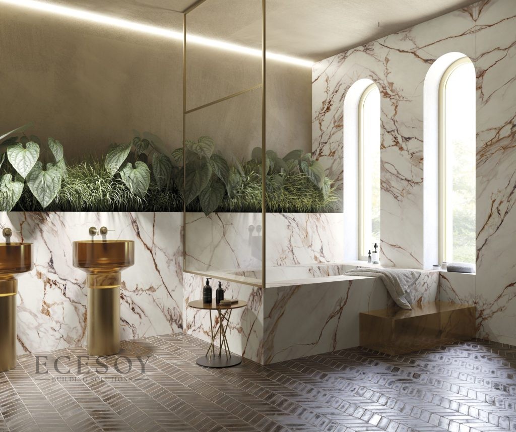 Kırmızı ve altın damarlı Light Red Calacatta porselen ile kaplı lüks banyo duvarı, küvet ve altın rengi lavabolar.