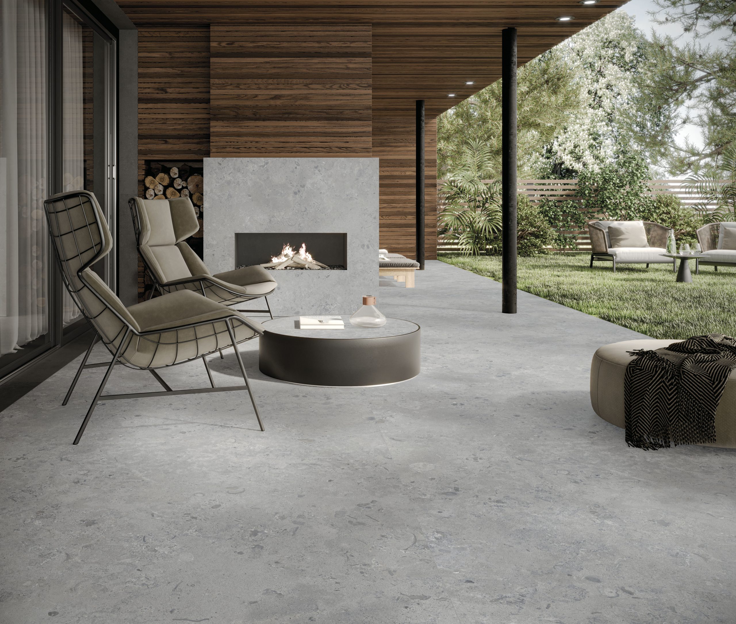 Modern bir terasta zemin ve şömine kaplaması olarak kullanılan gri, doğal taş dokulu Lapidura Norwegian Stone porselen yüzey.